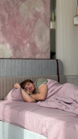man lies in bed during the day and enjoys his life