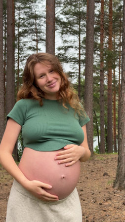 Happy pregnant young woman walking in the park with a big bellyの写真素材