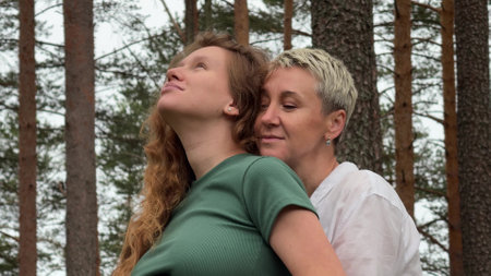 two women in the park hugging, pregnancy, family, mother and daughter or couple in loveの写真素材