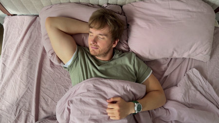 happy man sleeping in bed in the morning, top viewの写真素材