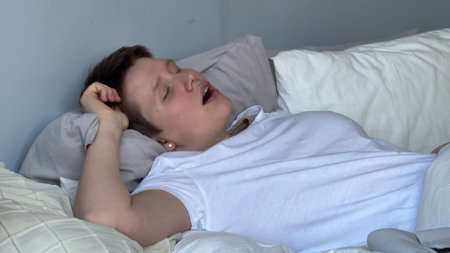 young woman sleeps in bed during the day and has breathing problems, apnea, open mouth, snoringyoung...