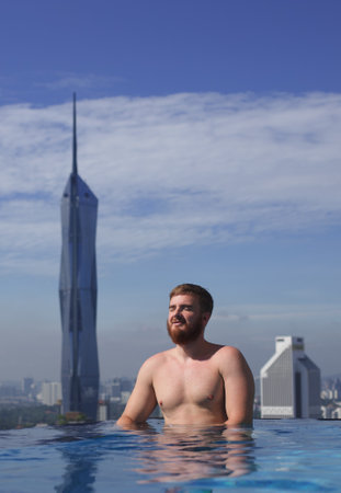 Happy young man in the swimming pool in a hotel on a roof in Malaysia, Kuala Lumpur