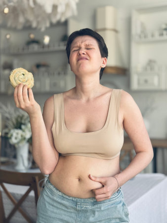 young modern woman suffers from craving for flour. concept weight loss, unhealthy food, fat, nutrition problems, excess weightの写真素材