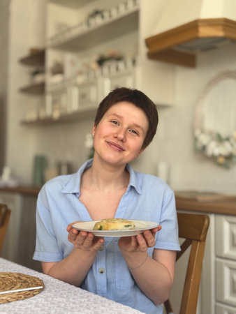 young smiling woman enjoying the aroma of food on a plateの写真素材