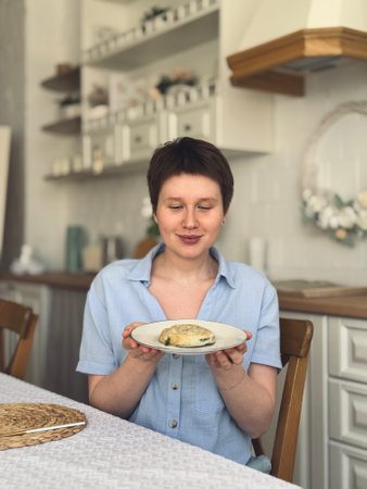 young smiling woman enjoying the aroma of food on a plateの写真素材