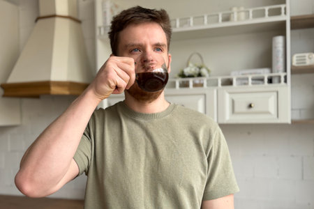 Enjoying a fresh cup of coffee in a modern kitchen, enveloped in comforting warmthの写真素材