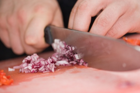 Chef cutting the onions on a wooden board