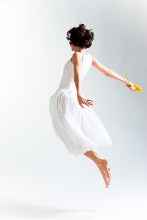 Young woman in with dress flying with flowerの写真素材