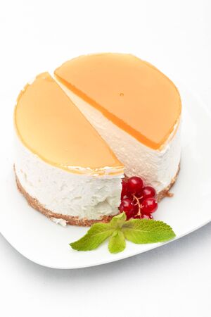 A piece of cheesecake on a plate decorated with red currant and mintの写真素材