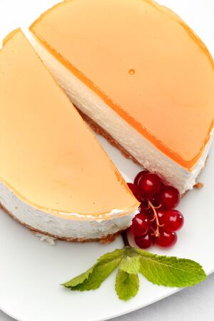 A piece of cheesecake on a plate decorated with red currant and mintの写真素材