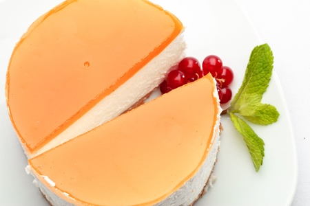 A piece of cheesecake on a plate decorated with red currant and mintの写真素材