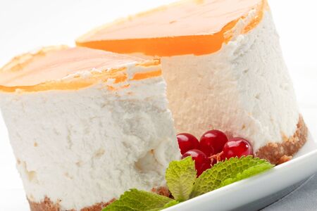 A piece of cheesecake on a plate decorated with red currant and mintの写真素材