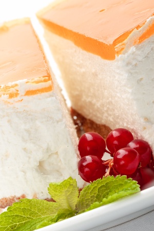 A piece of cheesecake on a plate decorated with red currant and mintの写真素材