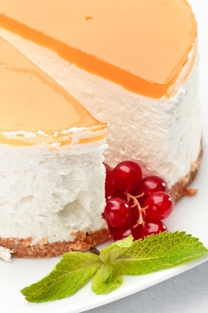 A piece of cheesecake on a plate decorated with red currant and mintの写真素材