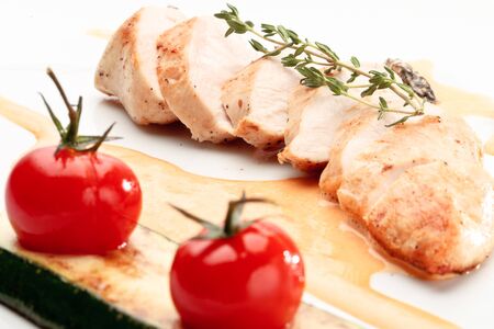 Chicken breast decorated with tomatoes, rosemary and squash on a white backgroundの写真素材