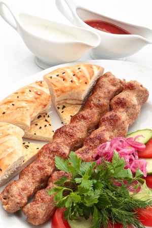 Chicken kebab with a side salad and bread decorated on a white backgroundの写真素材