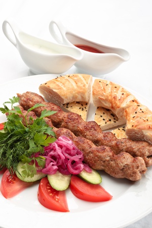 Chicken kebab with a side salad and bread decorated on a white backgroundの写真素材