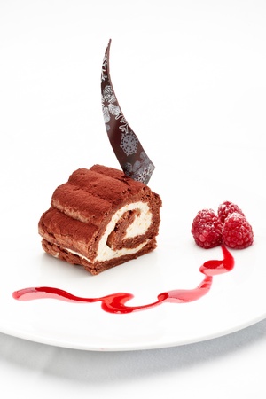 Chocolate roll with crud and mango cream decorated with raspberry and sauce on a white backgroundの写真素材