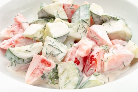 Close up of fresh vegetable salad with sour cream and greens on a white backgroundの写真素材