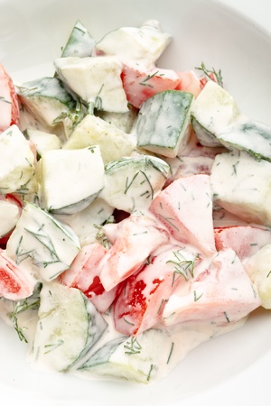 Close up of fresh vegetable salad with sour cream and greens on a white backgroundの写真素材