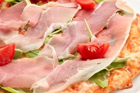 Close-up of pizza with parma ham and arugula decorated with vegetables decoratedの写真素材