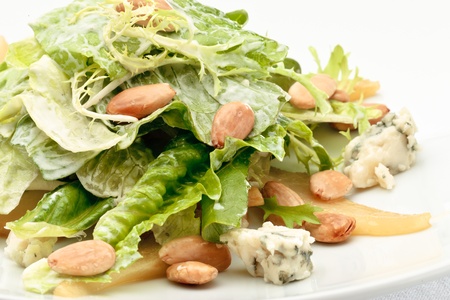 A portion of roquefort cheese salad decorated with arugula and pine nuts on a white plateの写真素材