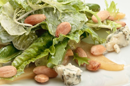 A portion of roquefort cheese salad decorated with arugula and pine nuts on a white plateの写真素材