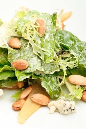 A portion of roquefort cheese salad decorated with arugula and pine nuts on a white plateの写真素材