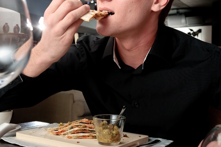 A handsome young man eating delicious arabian pita with rice and vegetable stuffing at a table elegantly servedの写真素材