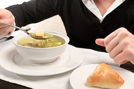 A young man eating fish soup, sitting at a table elegantly served in a restaurant, close upの写真素材