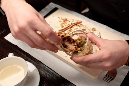 A handsome young man eating delicious arabian pita with rice and vegetable stuffing at a table elegantly servedの写真素材