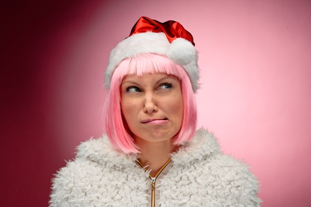 Portrait of a beautiful young woman in pink wig wearing christmas clothes over red background.の写真素材