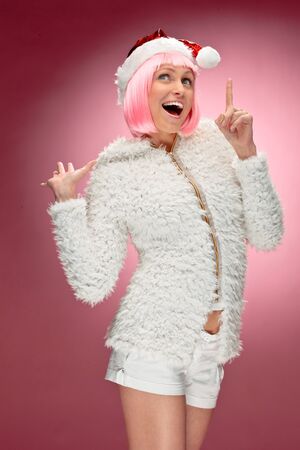 Studio portrait of a sexy young woman in pink wig dressed as Santaの写真素材