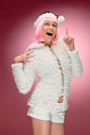 Studio portrait of a sexy young woman in pink wig dressed as Santaの写真素材