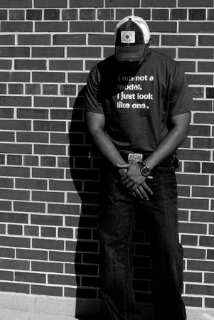 Attractive young African American male playing posing in a t-shirt and jeans against a brick wall.の写真素材