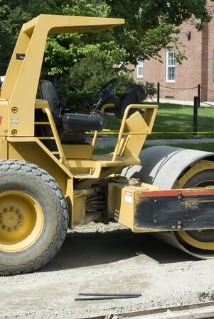 A yellow bulldozer idles on a road. の写真素材