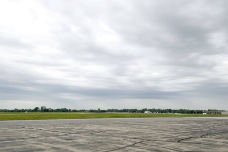 Wide shot of empty airport runway with cloudy skyの写真素材