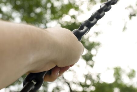 Photo of a hand gripping a chain from a tire swingの写真素材
