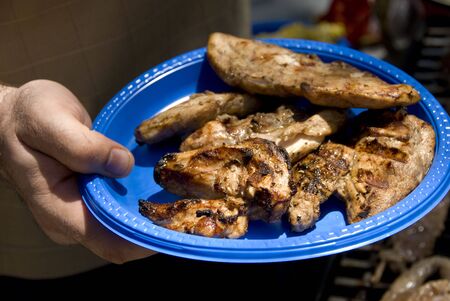 Adult male holding a plate of barbecued chicken