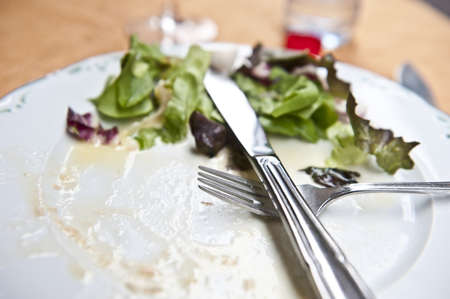A closeup of a plate that only has some salad left on it. 