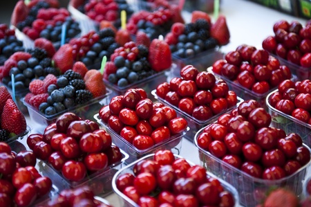 Cherries grouped together in mini clear containers; containers of mixed berries surround the containers of cherries. の写真素材