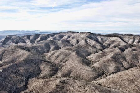 A dry desert view on a sunny day from a helicopter.