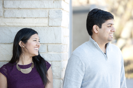 A young and happy Indian couple looking to the right on a sunny day.の写真素材