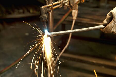 A metal fabricator utilizing a torch to heat up a piece of metal in order to shape it.の写真素材