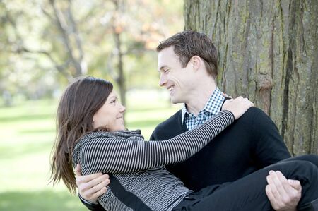 A young man carrying his wife at the park on a sunny day.