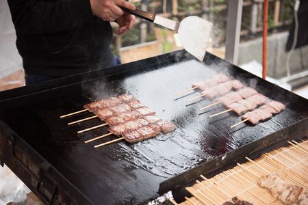 In the picture we can see a man preparing a street food. Some are prepared and kept infornt of the oven for sale.の写真素材