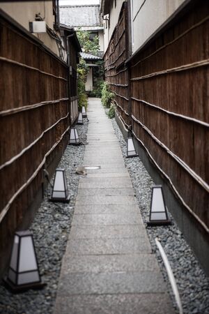 A narrow thin road between two buildings and small glass lamps on the roads can be seen in this image.の写真素材