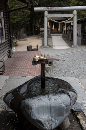 In the picture we can see water falling from the tap and at the background there are some tress and...