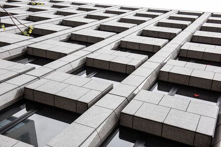 Stylish windows of a high rise building can be seen where the sun rays are getting reflected by the window glasses. A leaves and a branch also seen in this picture.の写真素材
