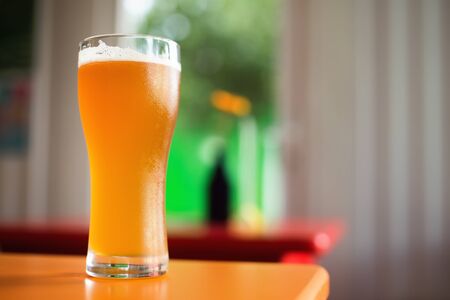 Glass of craft beer on table in bar. Colorful background. Shallow depth of fieldの写真素材